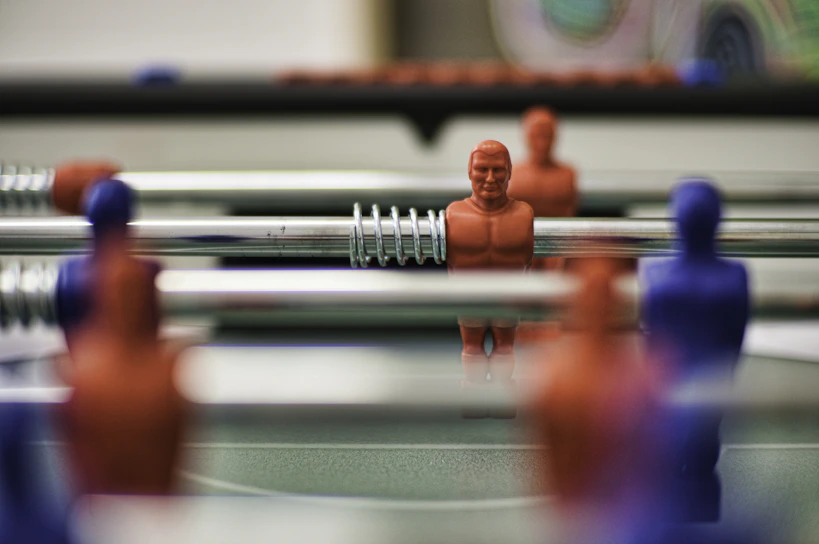 Children intensely focused during a foosball training session at žaidimo erdvė.