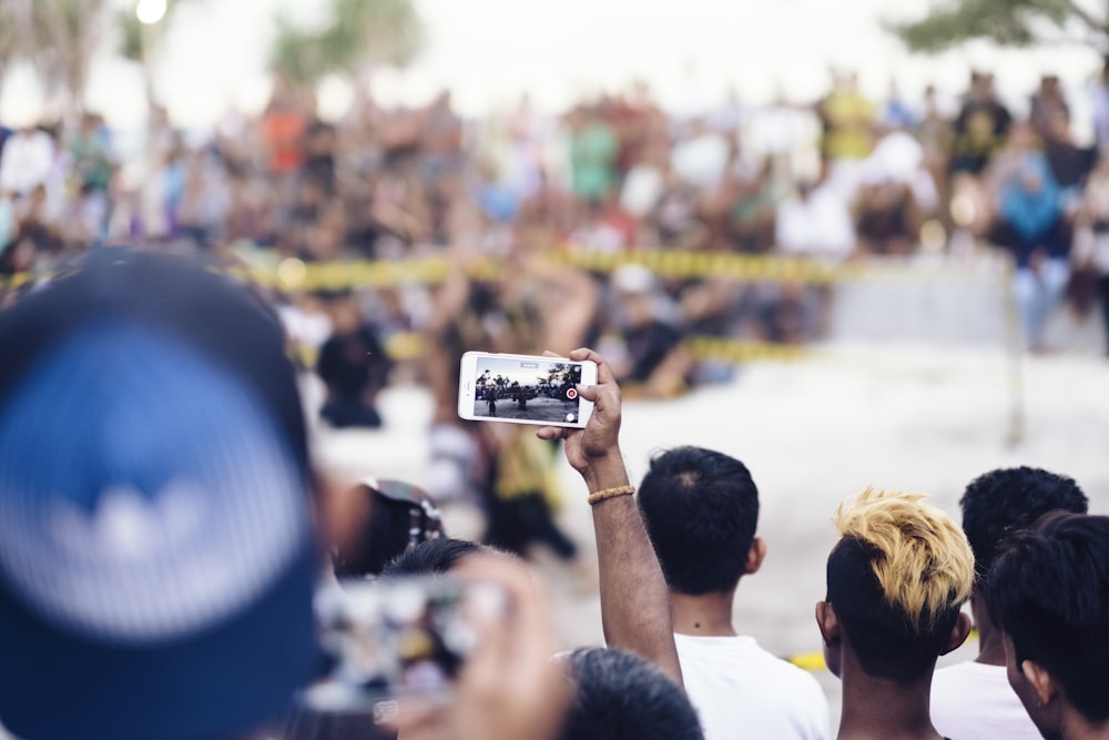 persona sosteniendo un teléfono inteligente blanco mientras toma una foto