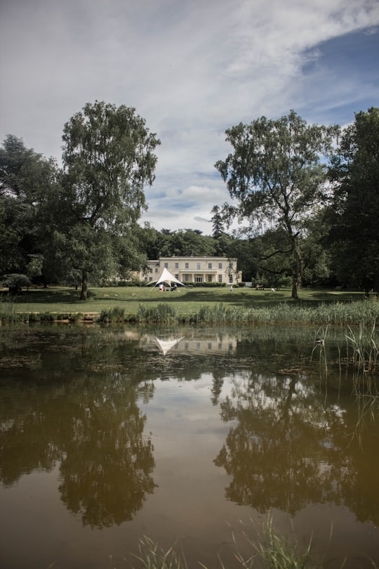 white house between trees under cloudy sky at daytime in Brandon Country Park United Kingdom