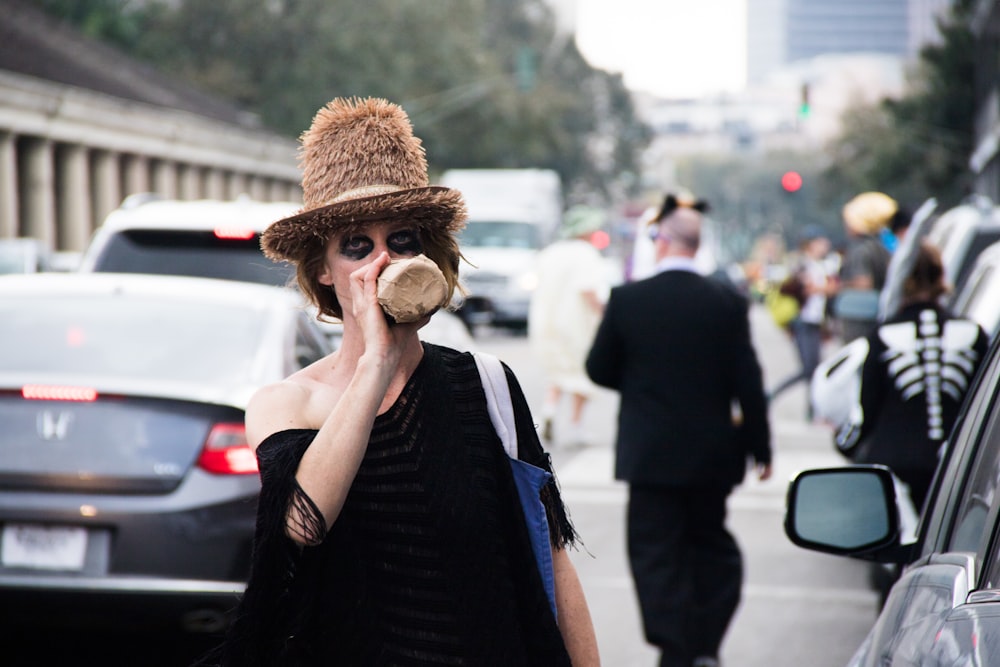 woman drinking from bottle while standing near traffic