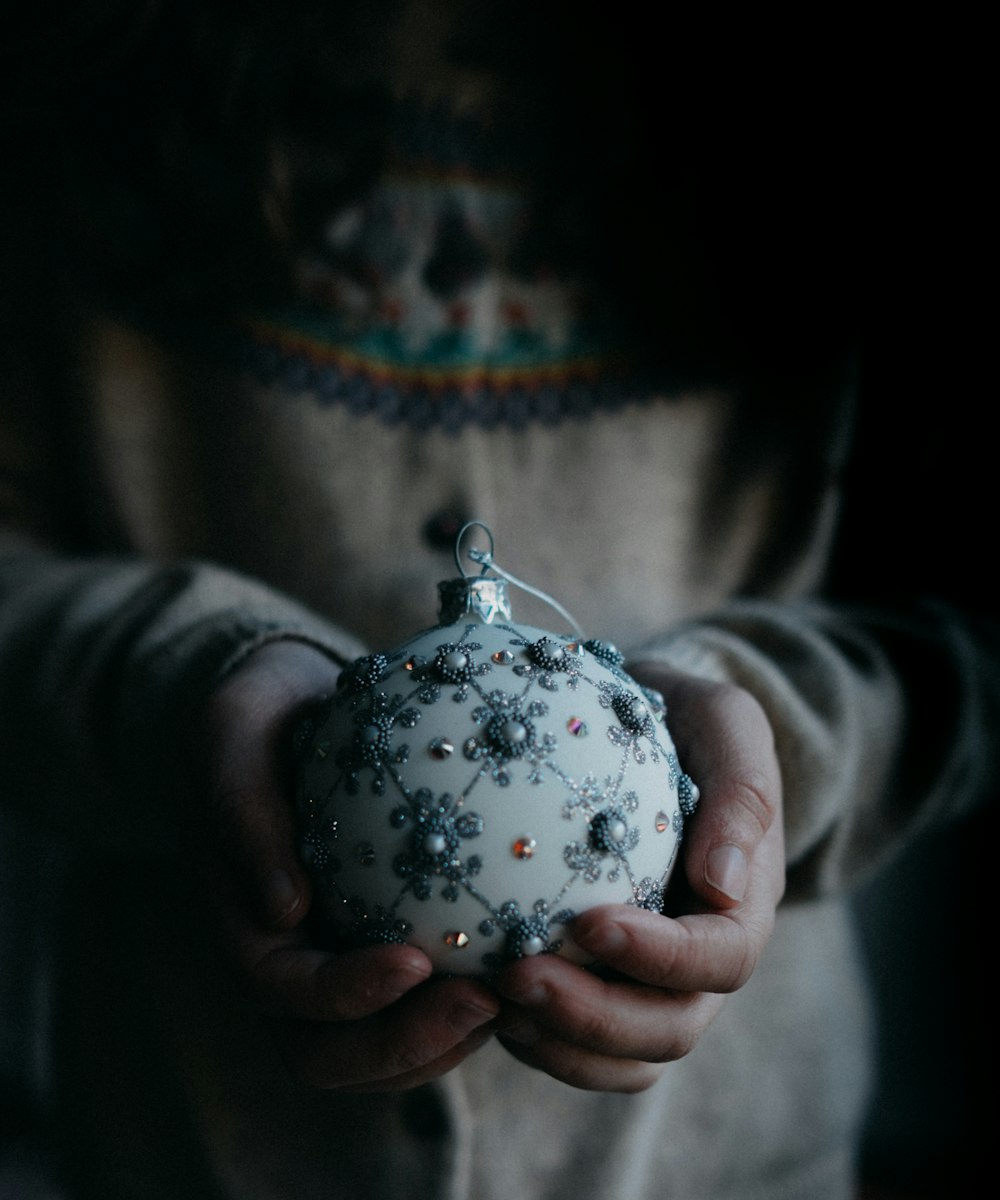 person holding white and grey ornament