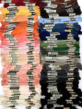 An array of colorful embroidery threads neatly arranged on a wooden table.