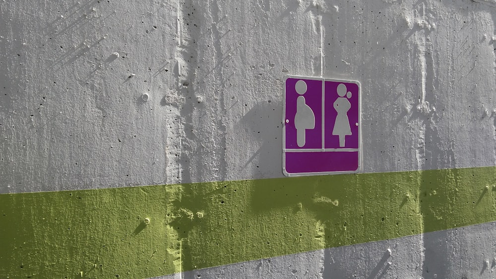 白く塗られた壁に紫色の女性と妊婦の看板