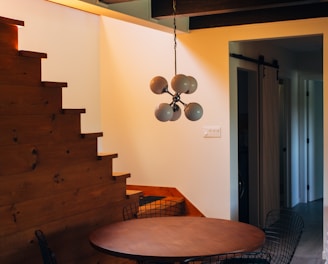 round brown wooden table and chairs under white pendant lamp