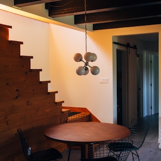 round brown wooden table and chairs under white pendant lamp