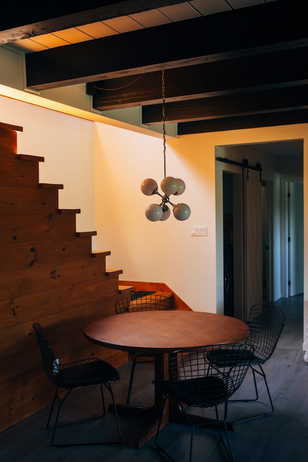 round brown wooden table and chairs under white pendant lamp