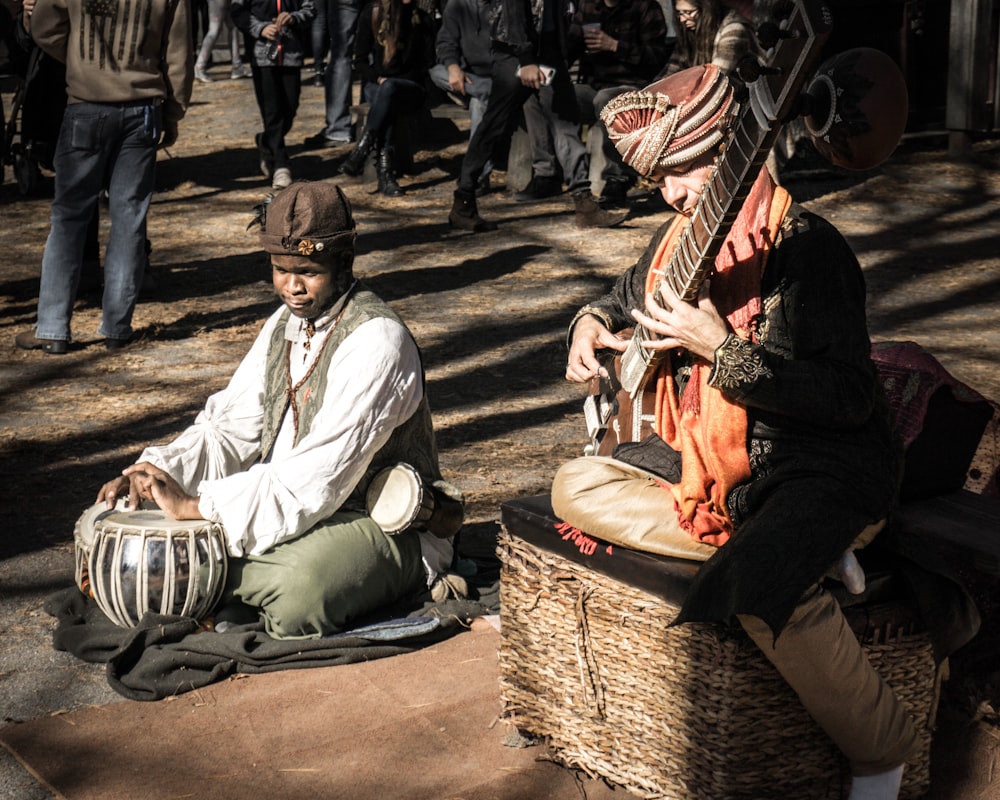 man playing on stringed instrument sitting on brown wicker basket