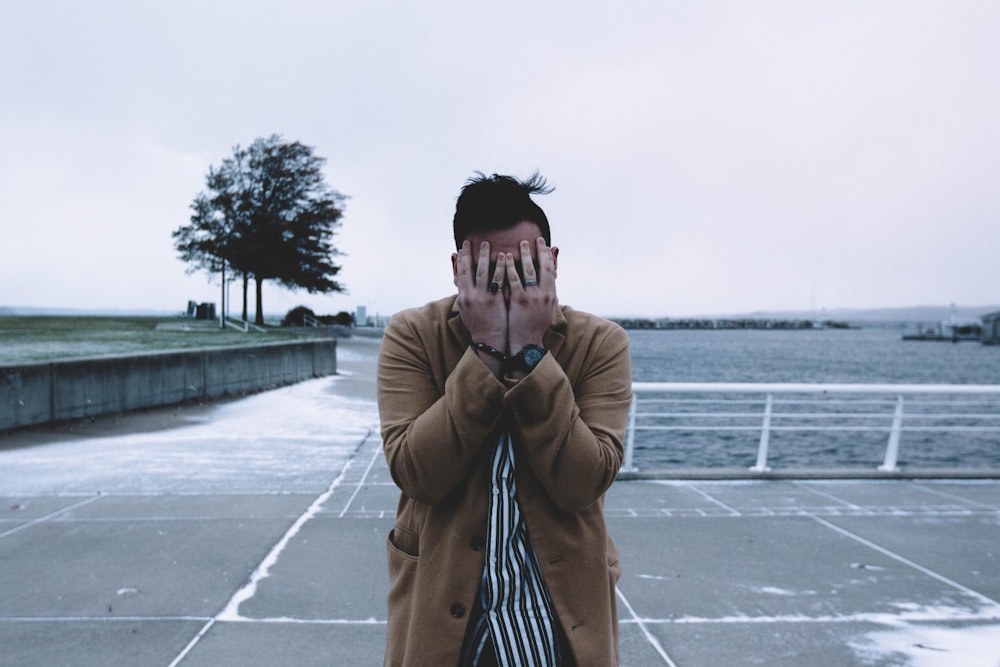 man covering face during daytime