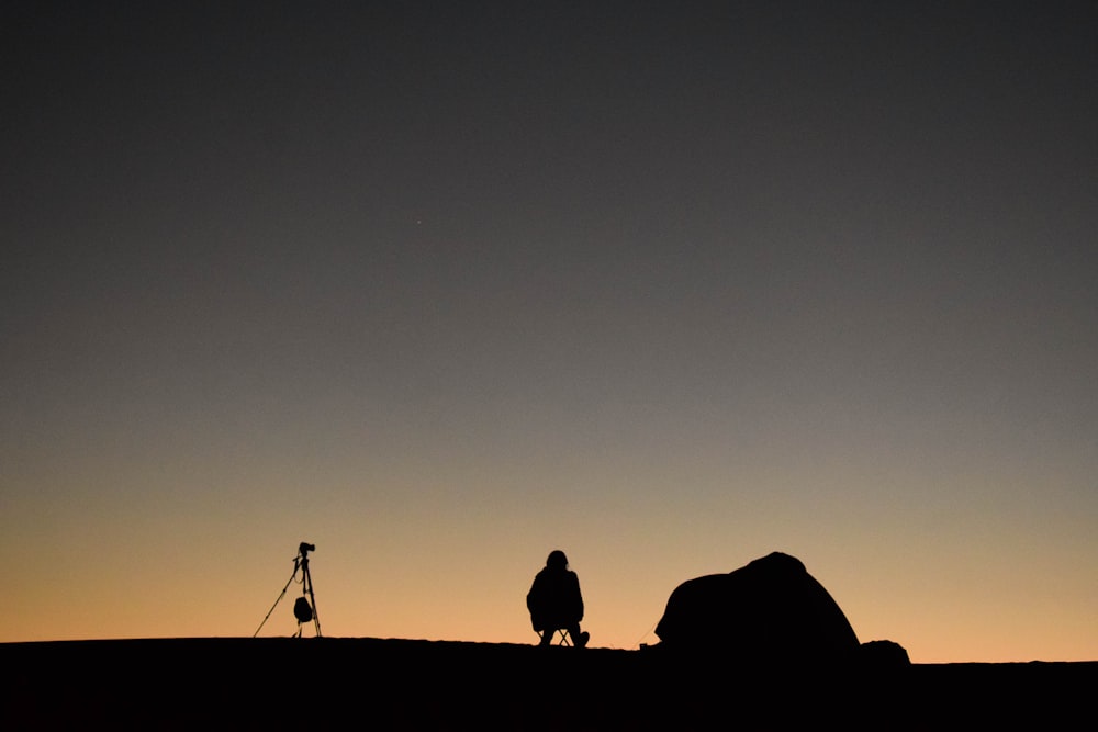 Foto da silhueta da pessoa sentada em uma cadeira de acampamento