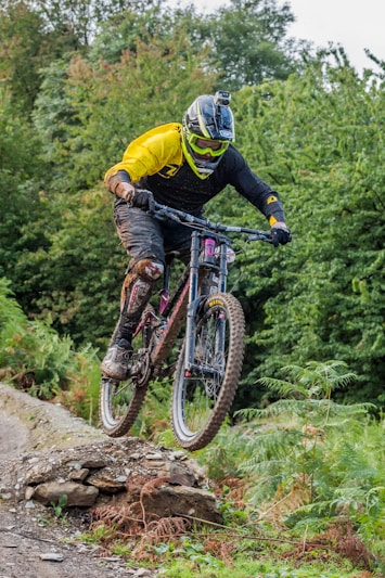 man riding on gray full-suspension mountain bicycle during daytime