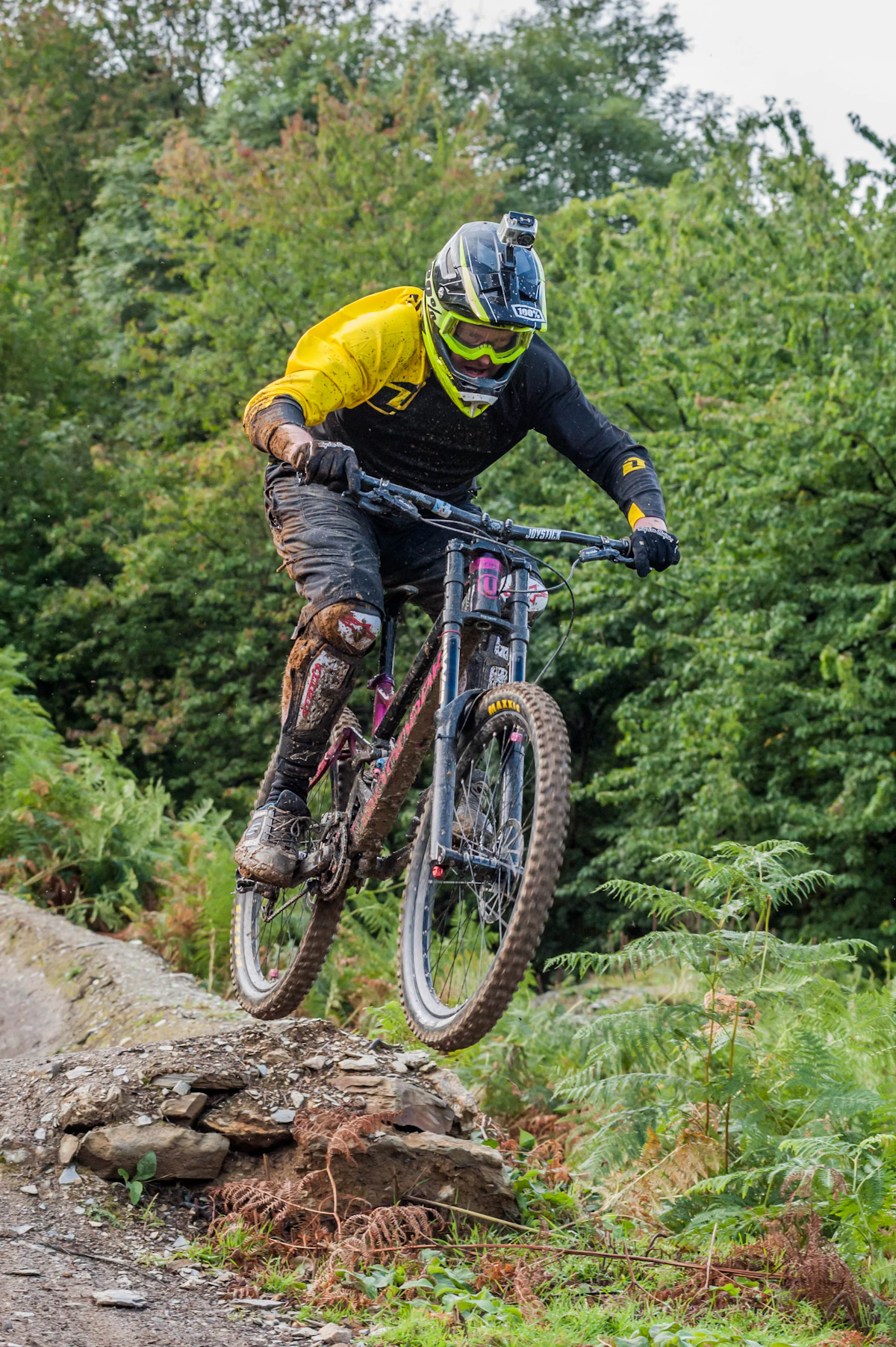 Downhill mountain biker in full-face helmet launching off a rock feature