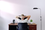 man holding his head while sitting on chair near computer desk