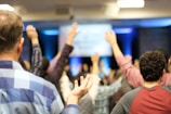 Hands raised in a participatory meeting with engaged attendees.