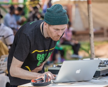 man using MacBook beside black and orange headphones