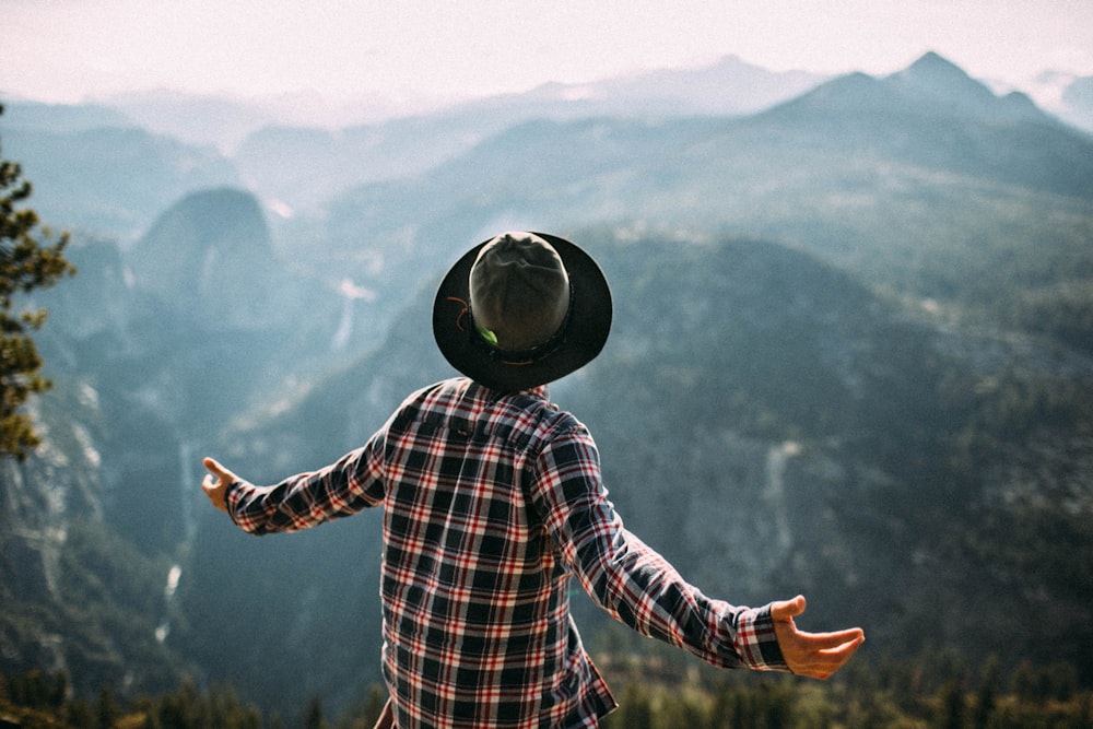 person standing on peak in front of green mountains