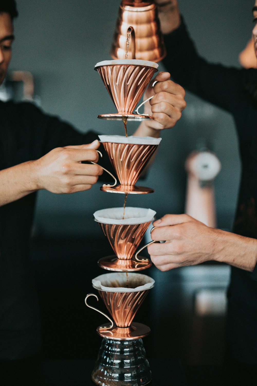 duas pessoas derramando café com xícaras empilhadas