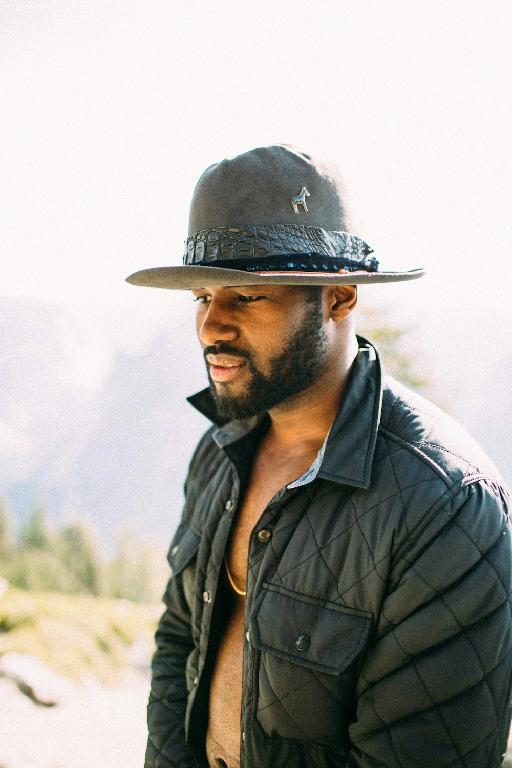 man wearing cowboy hat and buffer jacket looking down outdoor