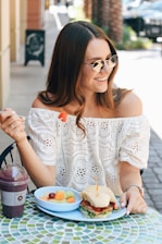 Smiling woman enjoying a fresh fruit salad outdoors on a sunny day