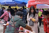 A journalist taking notes while interviewing a local resident in a busy market.