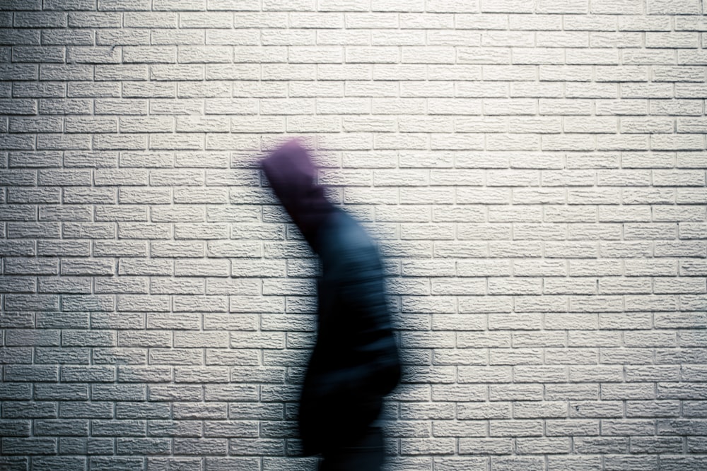 une image floue d’une personne debout devant un mur de briques