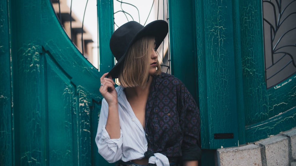 woman standing near teal wooden door