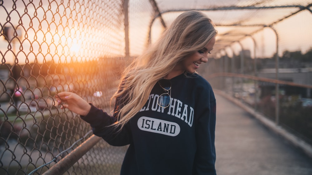 woman holding cyclone fence while smiling