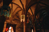 A dimly lit medieval tavern filled with shadowy figures around a wooden table.