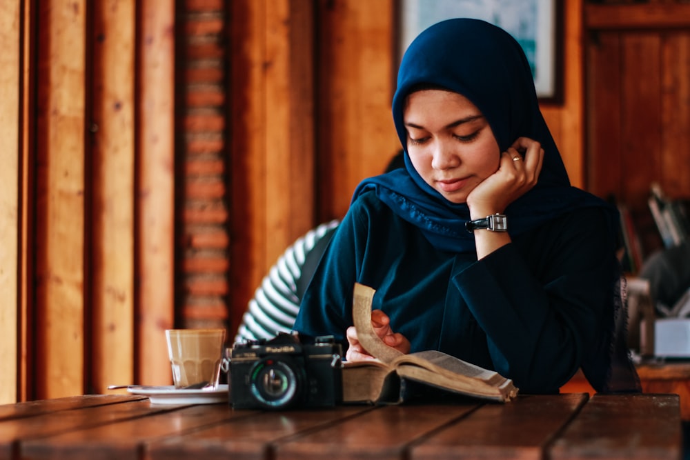 woman sitting beside table reading book