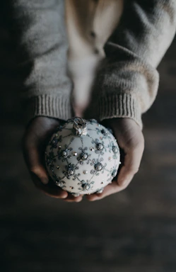 A warm, inviting photo of elderly hands gently holding a heart-shaped golden ornament.