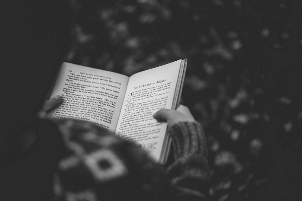 책을 읽는 사람의 회색조 사진