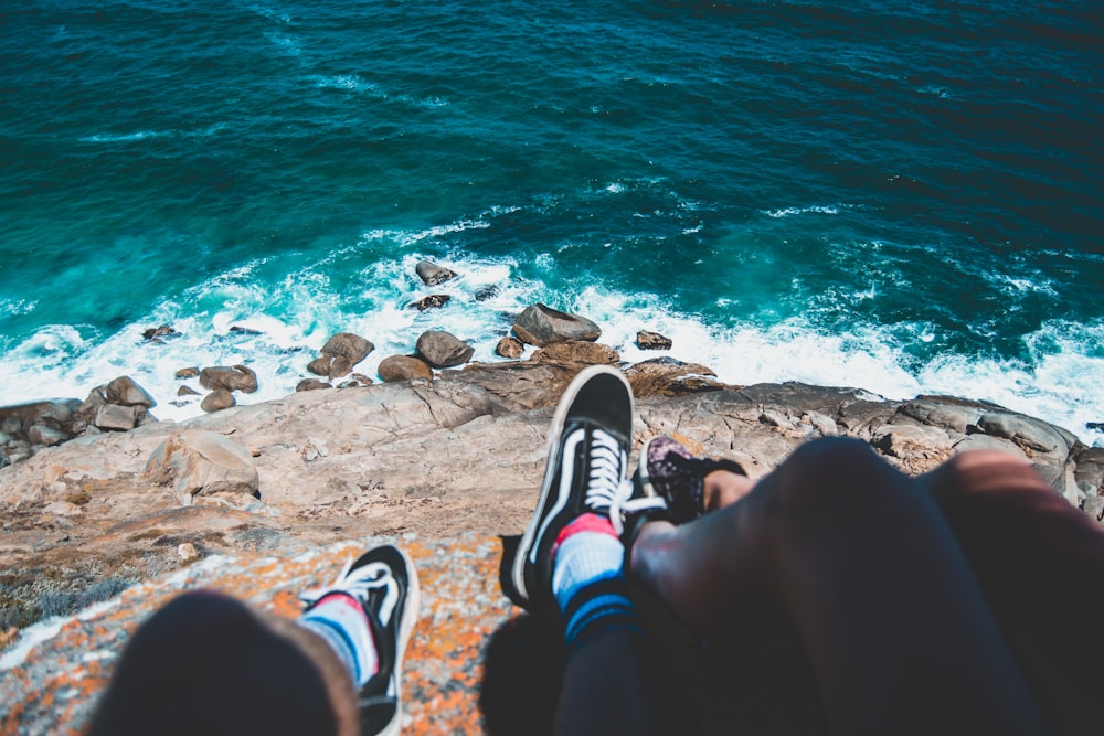 two people sitting on cliff