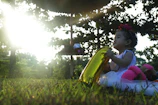 Riya Sanvi giggling softly while holding a pastel pink balloon under warm sunlight.