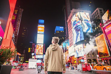 man standing on road infront of high-rise buildi