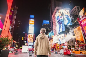 man standing on road infront of high-rise buildi