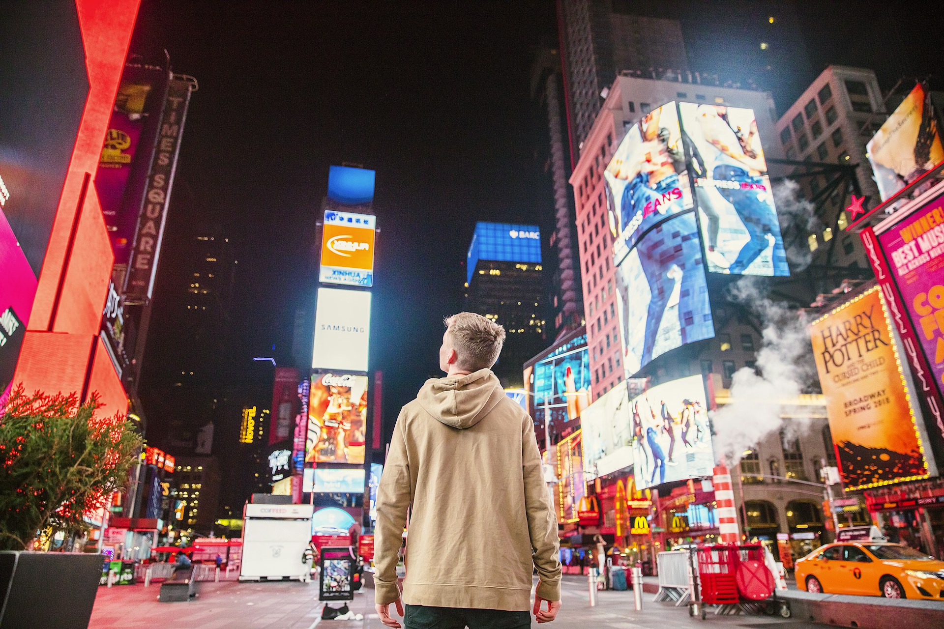 man standing on road infront of high-rise buildi