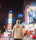 man standing on road infront of high-rise buildi