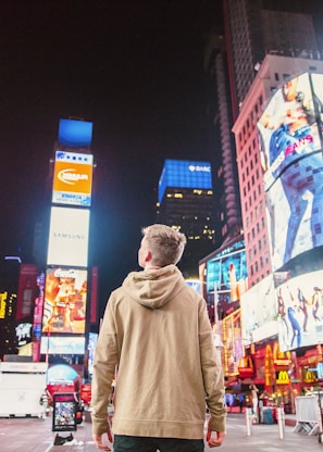 man standing on road infront of high-rise buildi