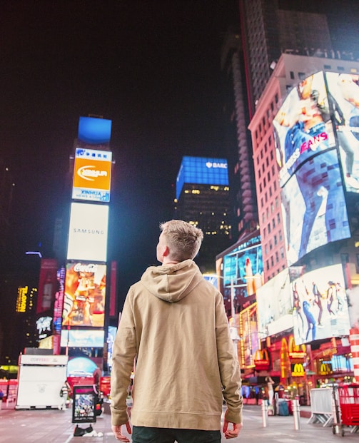 man standing on road infront of high-rise buildi