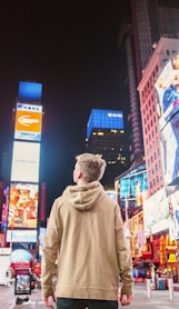 man standing on road infront of high-rise buildi