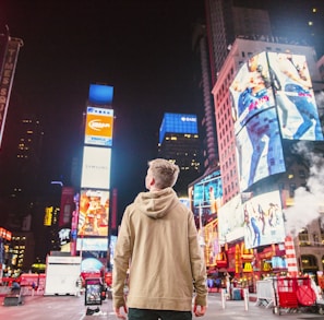 man standing on road infront of high-rise buildi