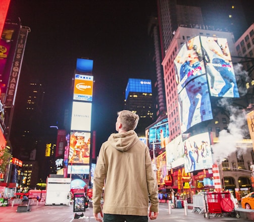 man standing on road infront of high-rise buildi