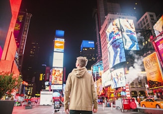 man standing on road infront of high-rise buildi