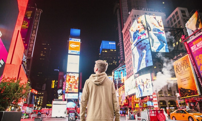 man standing on road infront of high-rise buildi