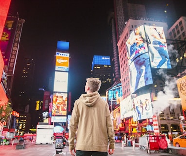 man standing on road infront of high-rise buildi