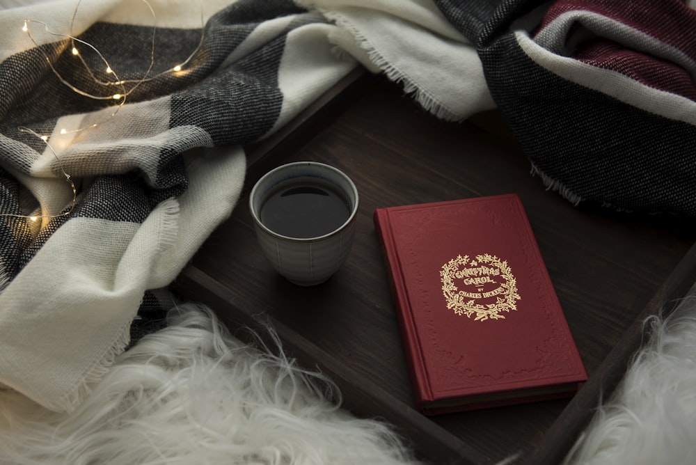 white ceramic coffee mug with coffee besides red envelope