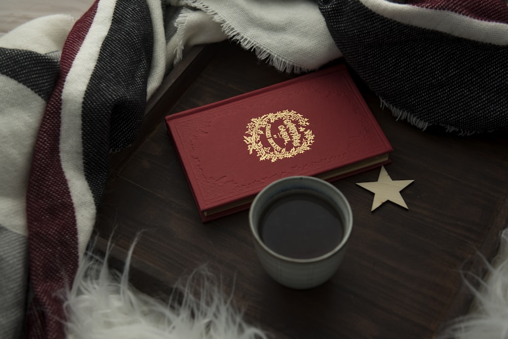 red hardbound book beside cup of coffee