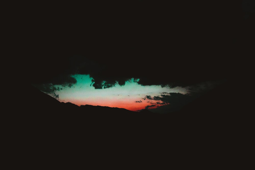 a dark sky with a green and red cloud