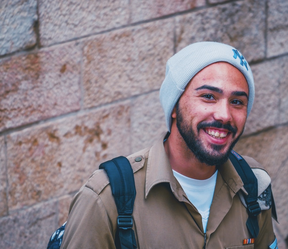 uomo in cappello a maglia bianco che sorride mentre ha foto