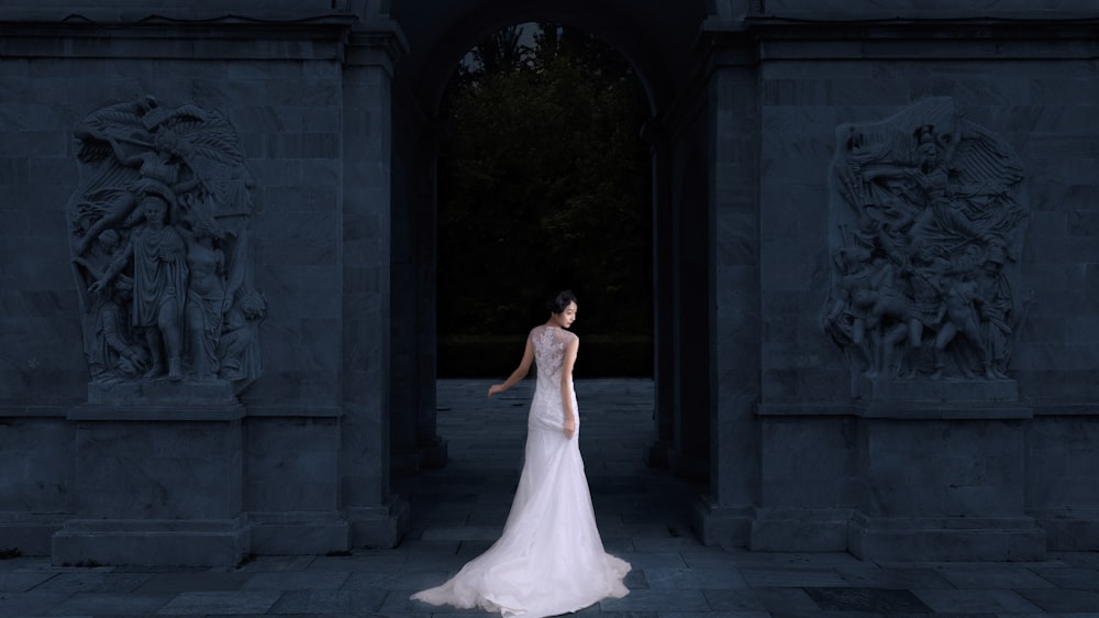mujer con vestido de novia blanco sin mangas cuerpo mirando hacia el edificio mientras que la cara mirando hacia los lados