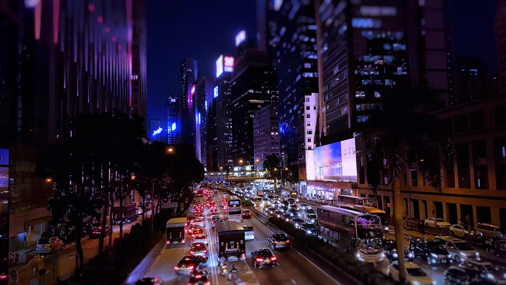 cars travelling on road between buildings at night time